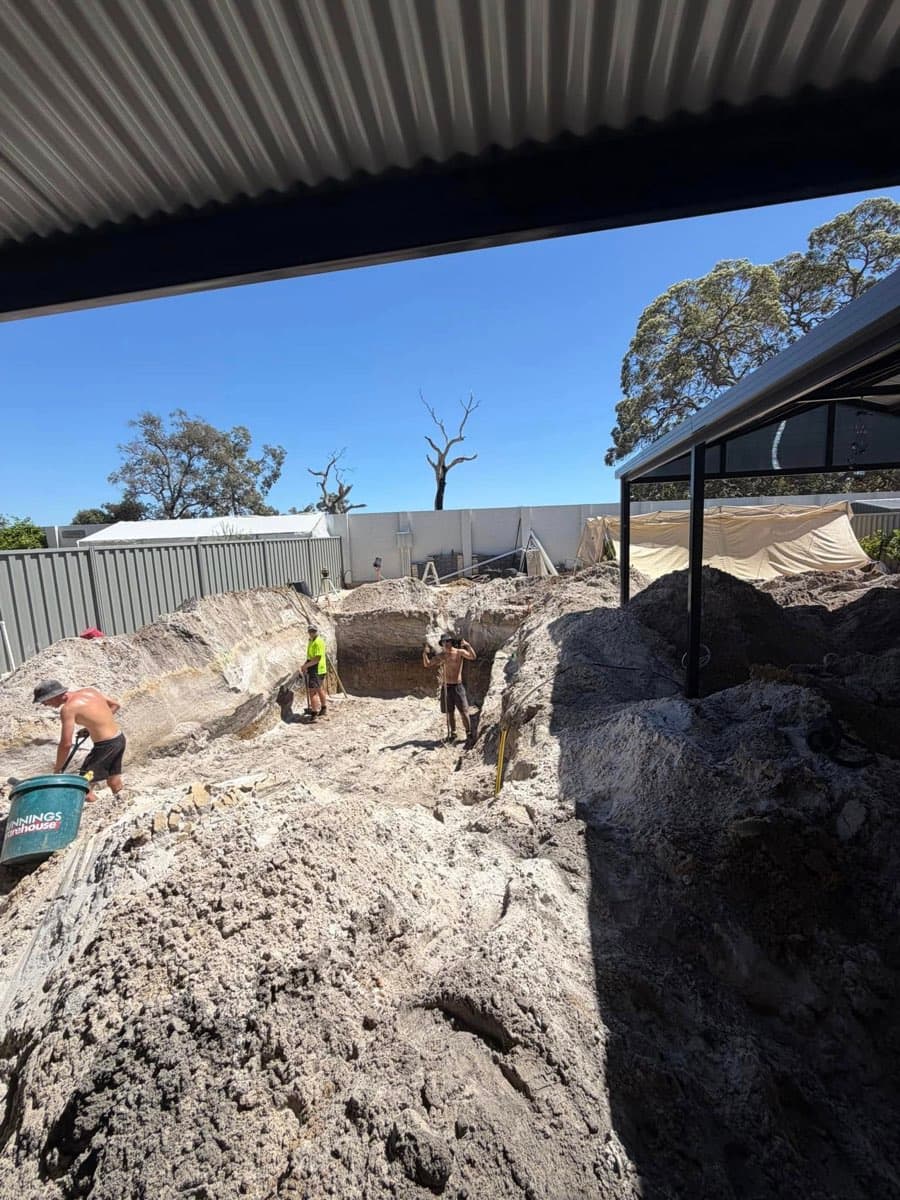 Tight-access pool excavation in progress — crew on site, hole dug