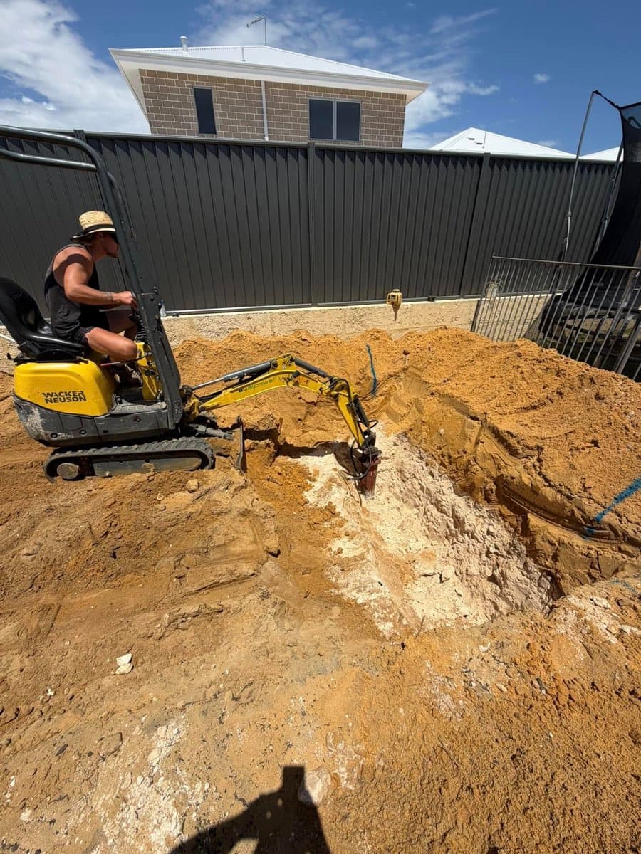 Mini-excavator working inside an excavation