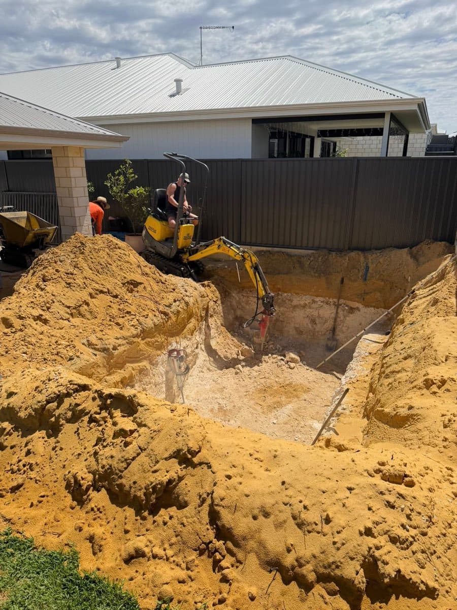Mini-excavator digging pool, sand piled outside the pit